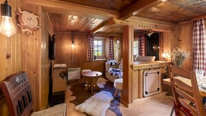 L’intérieur d’un chalet en bois accueillant, avec un coin repas, un canapé, une petite table et une cheminée.