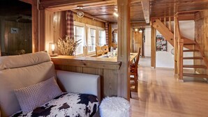 L’intérieur chaleureux d’un chalet avec un plafond en bois, un coin repas et un escalier.