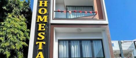 Un edificio a più piani con un cartello ben visibile che riporta la scritta "COZY 86 HOMESTAY".