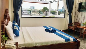 A hotel room with a bed, a desk, a chair, a telephone, and a window with curtains. - Cozy 86 Homestay (Can Tho)