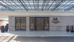 Una entrada de edificio moderna con techo de cristal, ventanas amplias y un logotipo destacado.