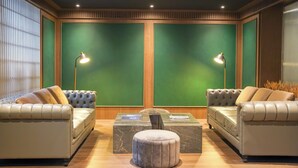 Una habitación con dos sofás de cuero, un reposapiés redondo y una mesa de centro de mármol.