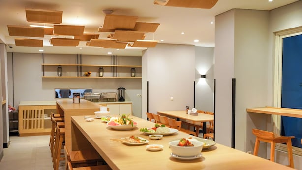 Una cocina moderna con encimeras de madera, una larga mesa de comedor y una variedad de platos.