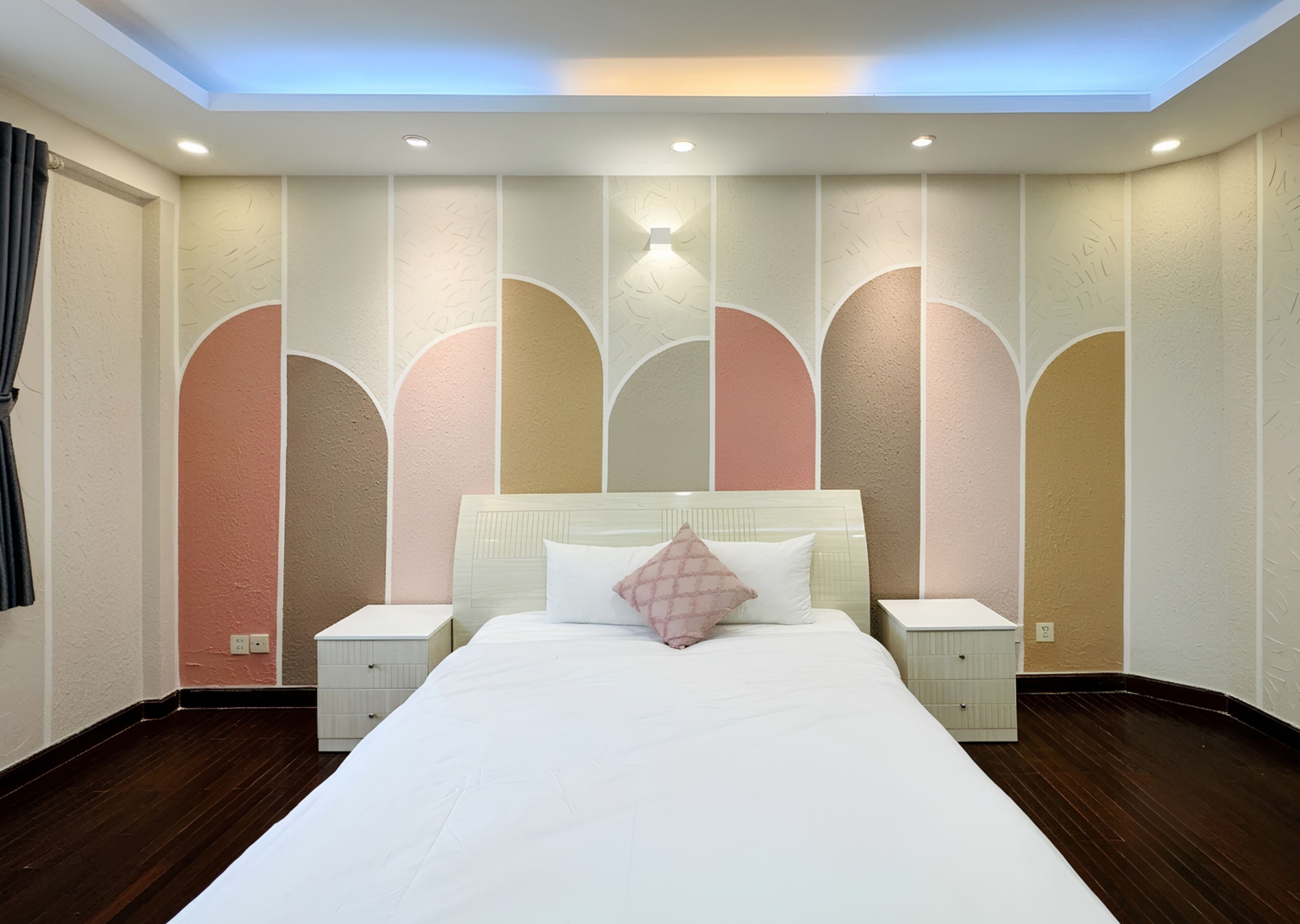 A bedroom with a large bed, two bedside tables, and a ceiling light.