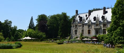 Un edificio grande e histórico con un jardín cuidado y un área de estar al aire libre.