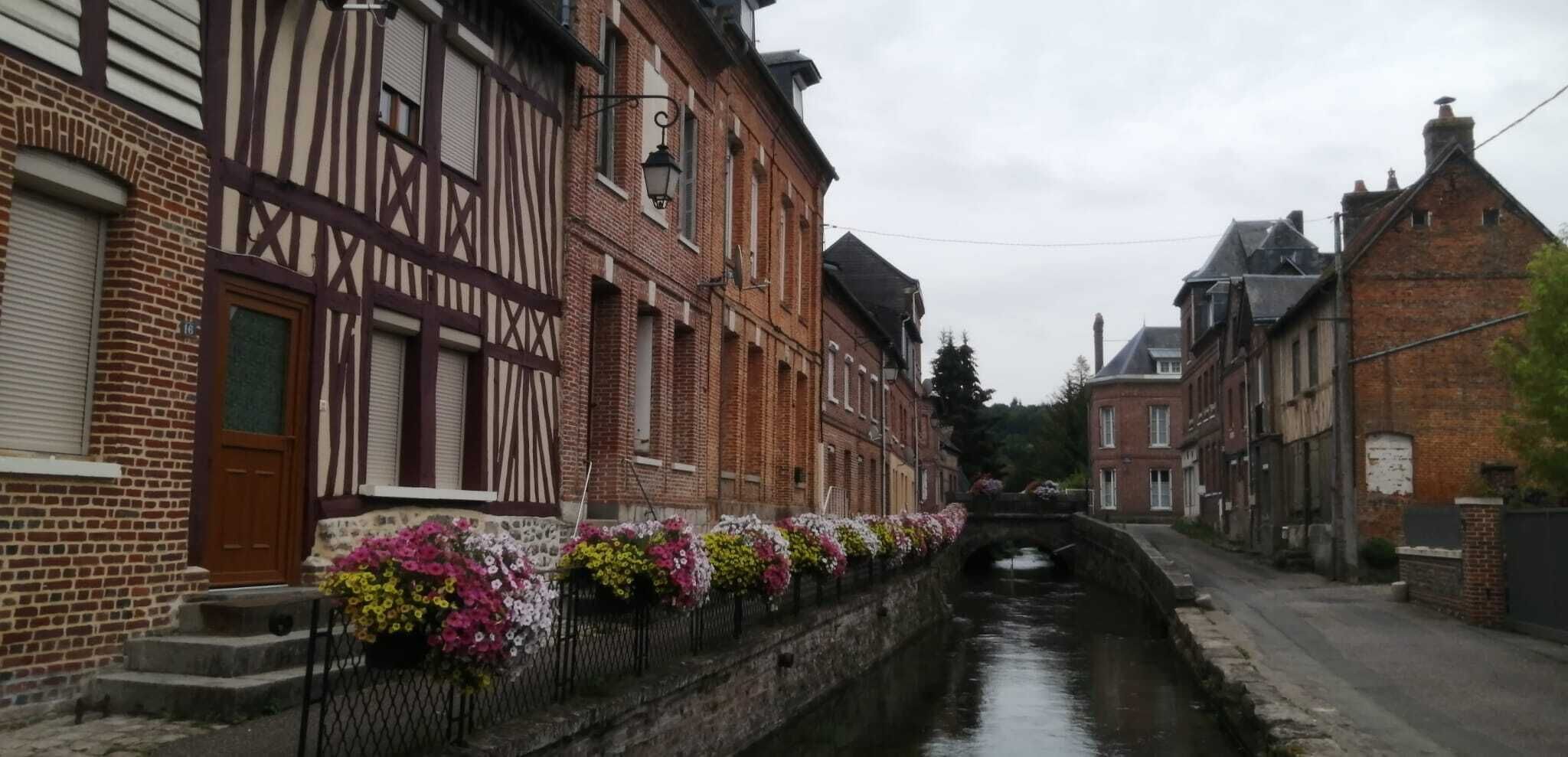A narrow canal flanked by traditional half-timbered houses with flower boxes along the canal.