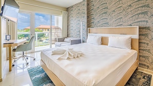 A hotel room with a large bed, a desk, a chair, and a view of the outside. - Kralendijk Boutique Hotel (Kralendijk)