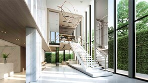 A spacious interior with a central staircase, large windows, and a minimalist design. - Comfy condo near BTS Asoke (Bangkok)