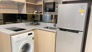 Una cucina moderna con lavatrice integrata, un forno a microonde e un frigorifero Samsung.