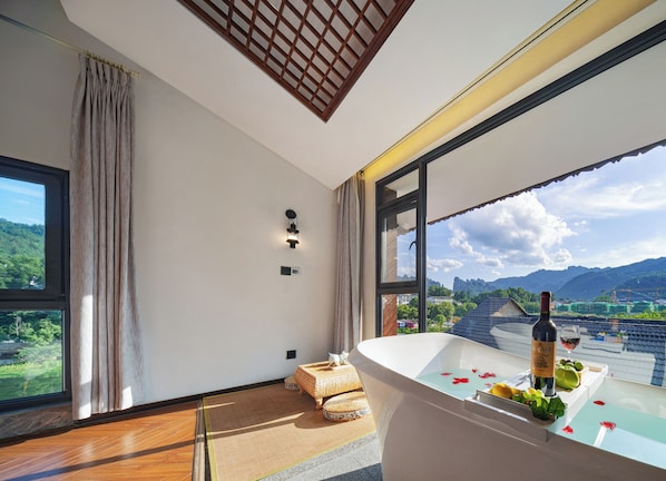 Una habitación moderna con un ventanal grande, una bañera y una botella de vino.
