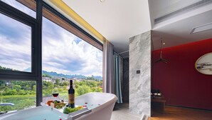 A modern bathroom with a large bathtub, a view of greenery and mountains, and a red accent wall. - Riverside Peak Lodge Zhangjiajie Wulingyuan National Park (Zhangjiajie)