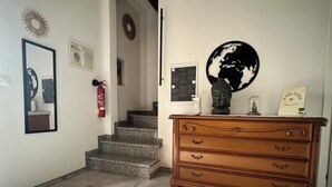 A hallway with a wooden dresser, a globe decoration, and a fire extinguisher.