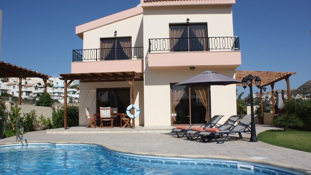 A two-story building with a swimming pool, outdoor seating, and a view of the surrounding area. - Seaside 2-bedroom Villa With Private Pool, Garden & Wifi Your Perfect Escape! (Pissouri)