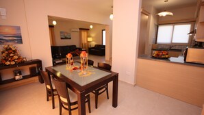 A modern dining area with a glass-top table, wooden chairs, and a view into the living room. - Seaside 2-bedroom Villa With Private Pool, Garden & Wifi Your Perfect Escape! (Pissouri)