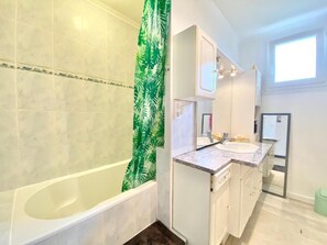 Un baño con bañera, lavamanos y espejo.
