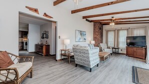 Un salón amplio con techo de madera, televisor, chimenea y comedor.