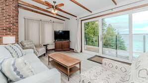 Un salón con televisor, sofá, mesa de centro y vista al agua.