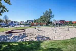 Guests can enjoy a sandy play area with a sandbox and swings.