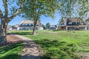 Stroll through a peaceful neighborhood with beautifully maintained lawns and unique homes featuring gabled roofs and varied window designs.