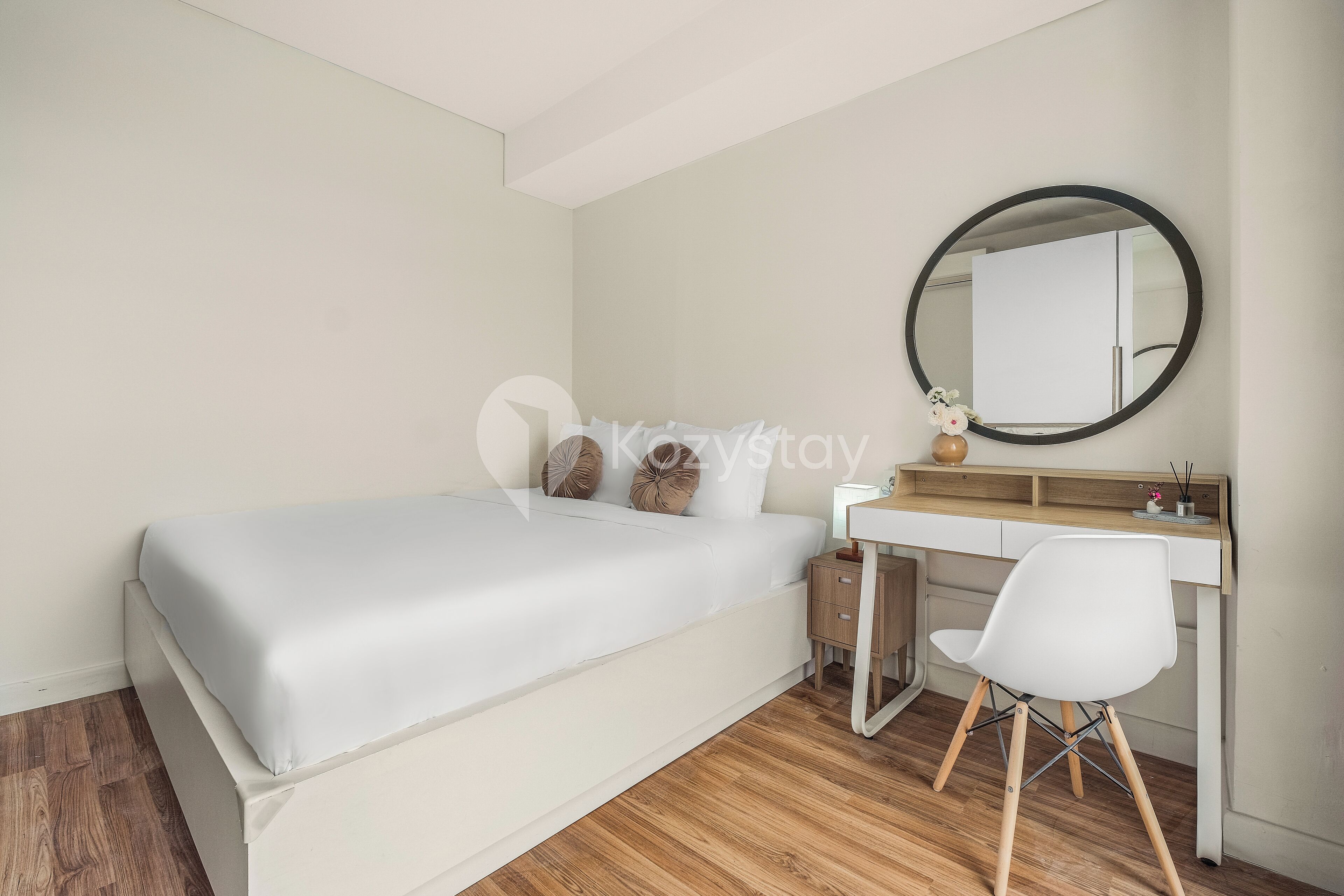 A bedroom with a bed, a desk, a chair, and a round mirror.