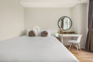 A neatly arranged bedroom with a bed, a desk, and a chair.