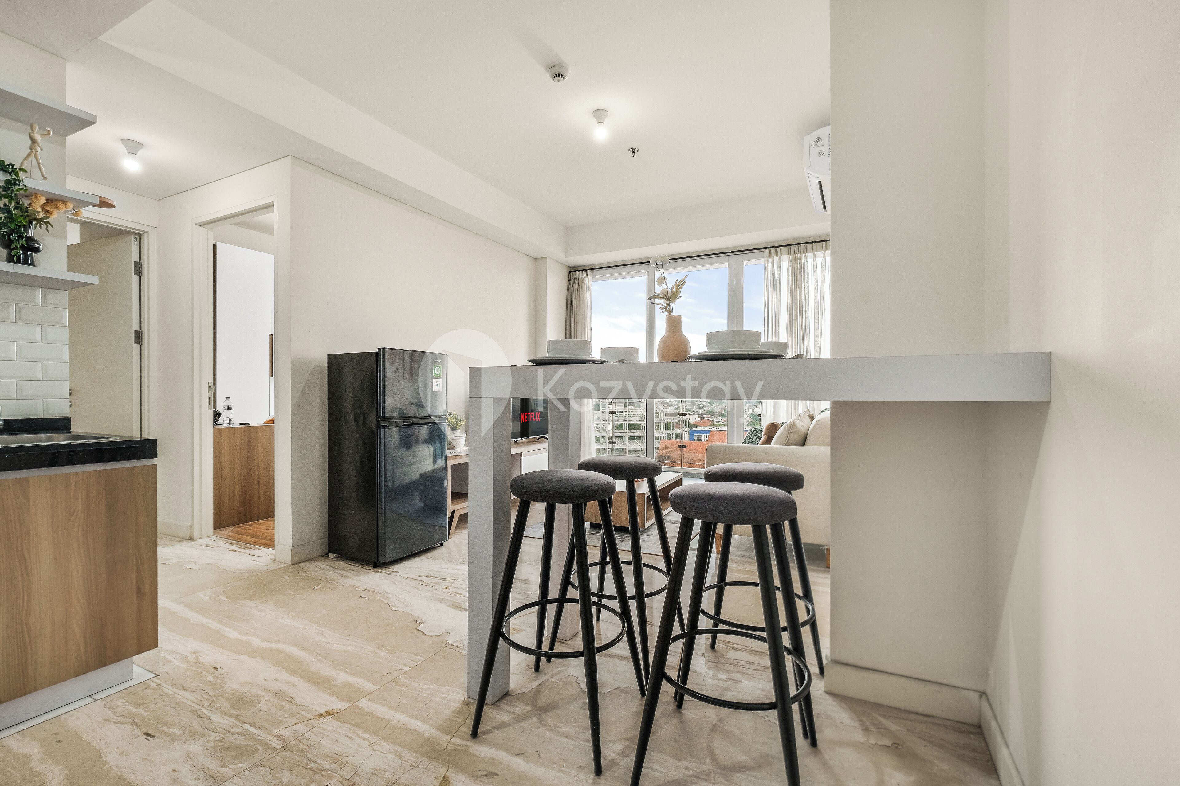 A modern kitchen with a black refrigerator, a wooden countertop, and a bar stool area.
