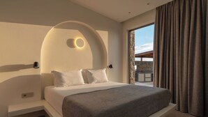 A modern bedroom with a large bed, a built-in bench, a circular light fixture, and a view of the outdoors.