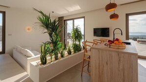 A modern kitchen with a wooden island, large windows, and a view of the outdoors.