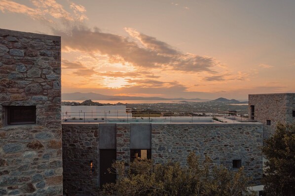 A stone building with a flat roof and a view of distant mountains during sunset.