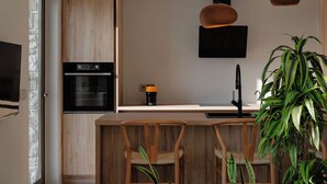 A modern kitchen with wooden cabinetry, a built-in oven, a coffee maker, and two pendant lights.
