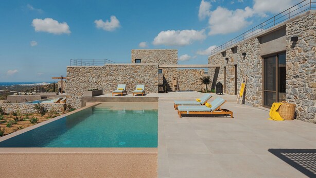 A poolside area with lounge chairs and a stone building.