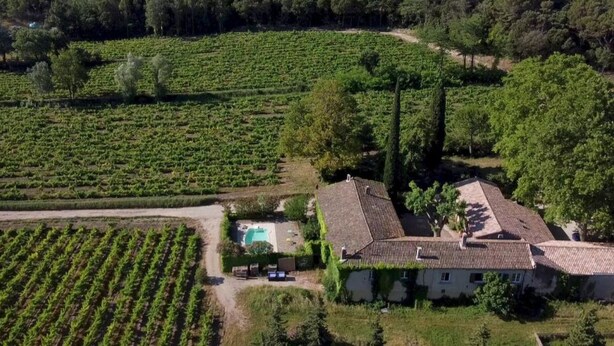 An aerial view of a vineyard with rows of grapevines, a house with a tiled roof, and a swimming pool. - Gite Grenache (Mondragon)