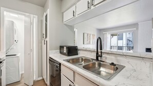 A modern kitchen with white cabinetry, a double sink, and a microwave.