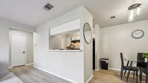 Una cocina moderna con gabinetes blancos, una isla integrada y un comedor con una mesa y sillas negras.