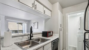 Una cocina moderna con un lavamanos doble, electrodomésticos de acero inoxidable y armarios blancos.