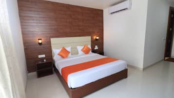 Ein Schlafzimmer mit einem Holz-Kopfteil, einem großen Bett mit weißer und orangefarbener Bettwäsche, zwei Nachttischen und Wandleuchten.