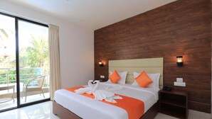Une chambre d’hôtel moderne avec un grand lit, une tête de lit en bois et un balcon doté d’une porte vitrée.