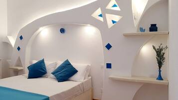 A modern bedroom with a curved ceiling, a bed with blue and white bedding, and decorative wall elements.