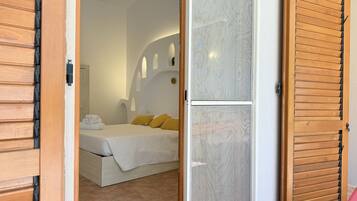 Un dormitorio con cama, almohadas y mesita de noche.
