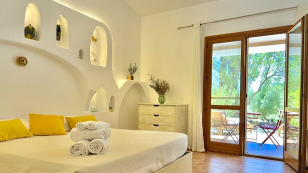 A bedroom with a large bed, a dresser, and a sliding glass door leading to an outdoor area. - [Green Hotel] Rural hotel double rooms (Orosei)