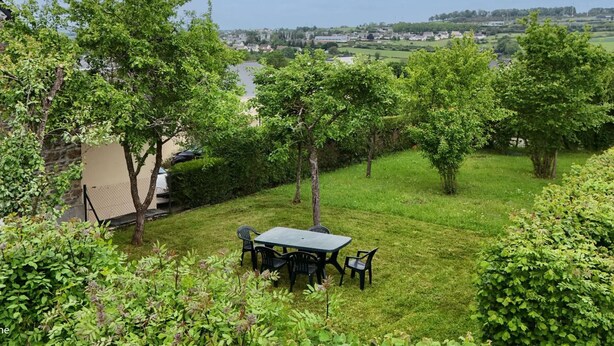 Eine grüne Außenanlage mit Tisch und Stühlen, umgeben von Bäumen und Blick auf eine ferne Stadt.