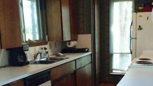 Una cucina con mobili in legno, un lavello, una lavastoviglie e un pavimento piastrellato.