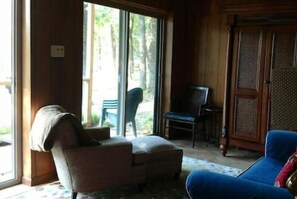 Relax in a traditional room with a sliding glass door leading to an outdoor area, featuring a sofa and armchair.