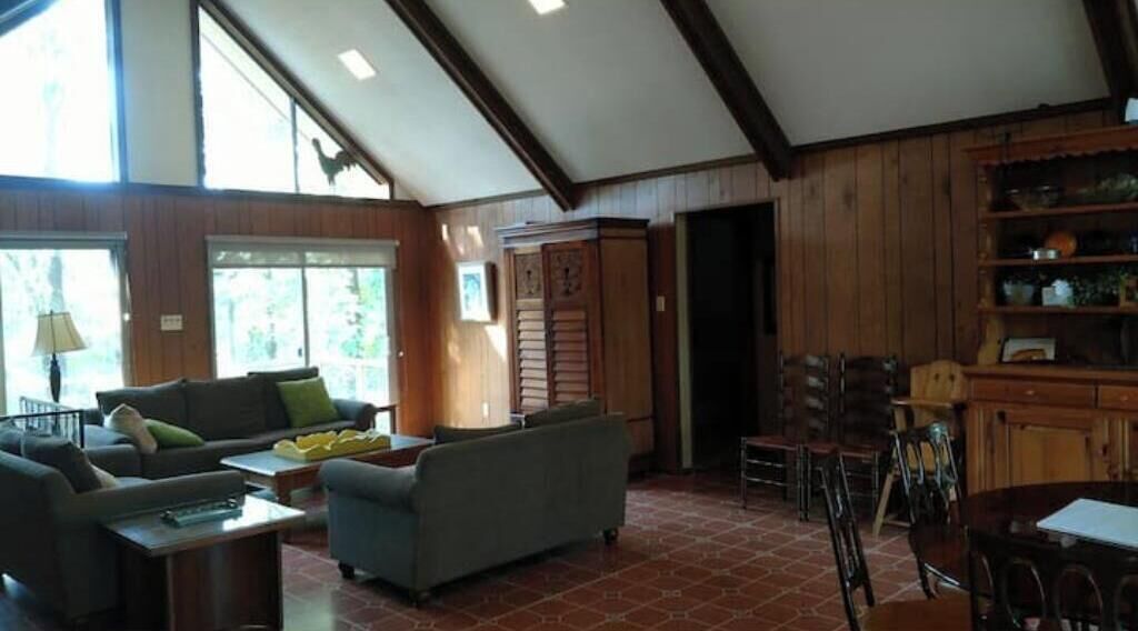 A spacious living room with a fireplace, a dining area with wooden furniture, and large windows allowing natural light.