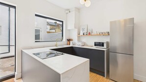 A modern kitchen with a central island, stainless steel appliances, and a view of the outside.