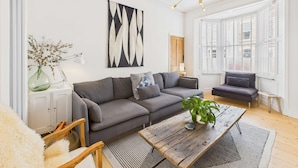 A modern living room with a grey sofa, a wooden coffee table, and a large abstract painting on the wall.