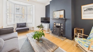 A living room with a fireplace, a sofa, a coffee table, and a television.