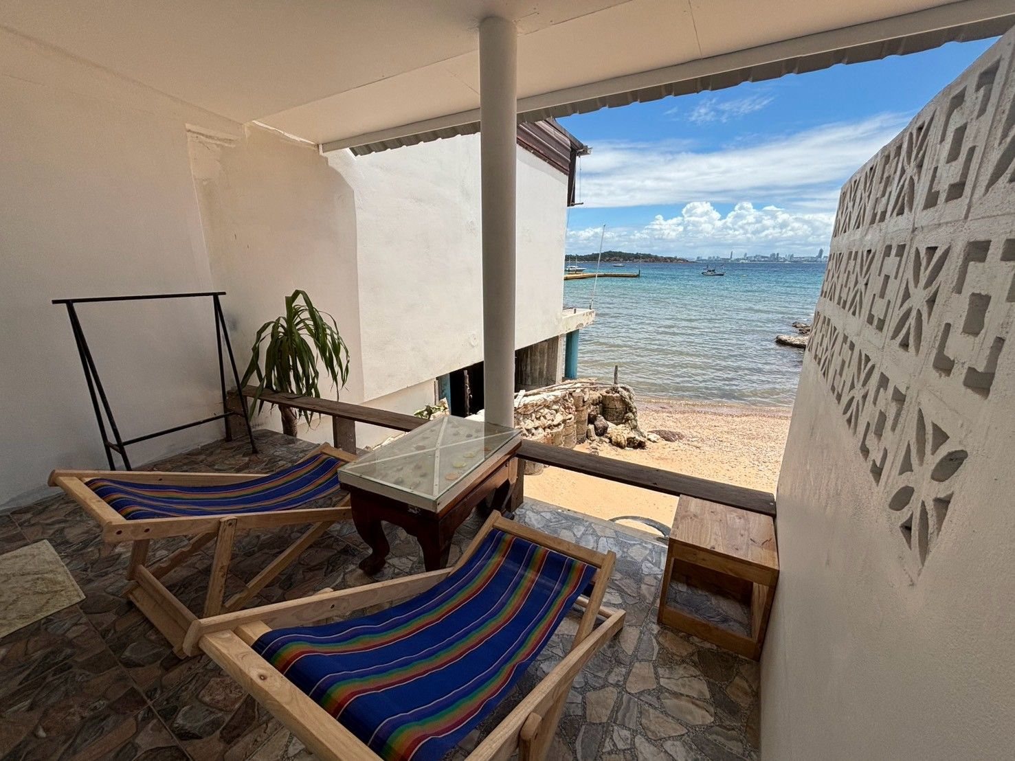 Un balcone con due poltrone di legno, un tavolo e vista sul mare.