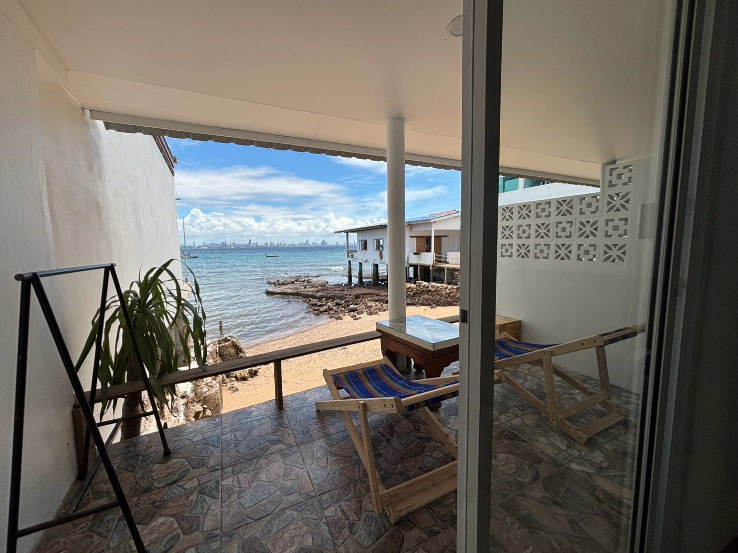 A balcony with a view of the sea, a lounge chair, and a small table.