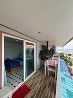 A balcony with a bed, a table, and chairs.